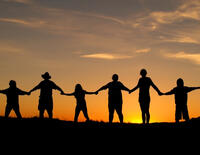 Six people holding hands in a line in front of sunset